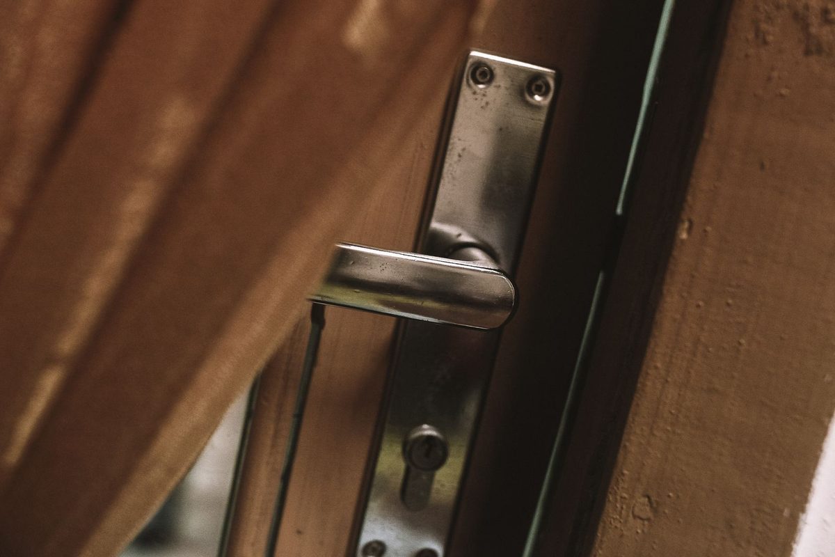 Door Frame Repair — Door handle and latch hardware being checked on a wooden door